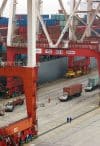 Containers being loaded onto a ship behind enormous crane gantrys at Yangshan deep water port